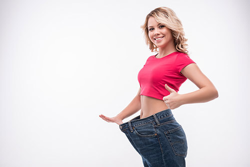 Woman who just lost weight holding large pants